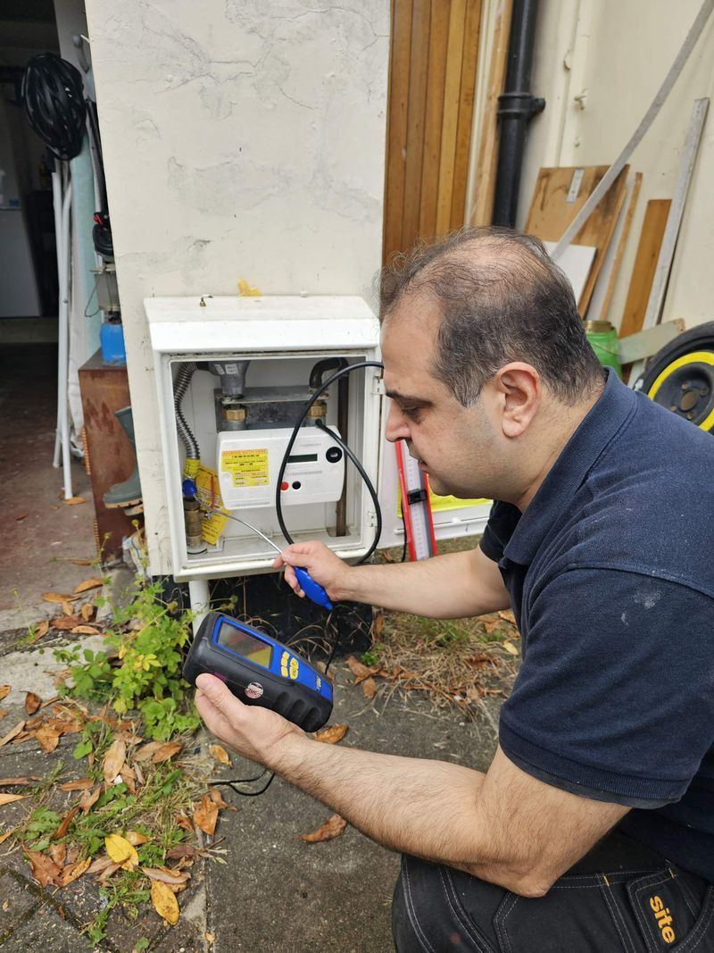 Engineer testing gas pipework at an external gas meter box with an electronic gauge